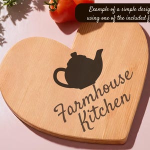 May include: A heart-shaped wooden cutting board with a black teapot silhouette and the words "Farmhouse Kitchen" in a script font. The text "Example of a simple design using one of the included files" is in a black rectangle.