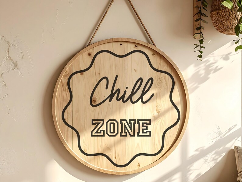 Peut inclure: Panneau rond en bois avec l'inscription "Chill ZONE" en noir. Le panneau est bord&eacute; d'un motif noir ondul&eacute; et est suspendu par une corde naturelle. Le bois a une finition claire et naturelle.