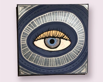 Puede incluir: Un ojo azul con pestañas amarillas y un iris blanco está pintado en un lienzo con un patrón de círculos concéntricos plateados y azules.