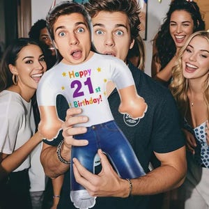 May include: A custom-shaped foil balloon featuring a person's face printed on the head, wearing a white t-shirt with the text "Happy 21st Birthday" in colorful letters, and blue jeans. The balloon is held by a person in a dark polo shirt.