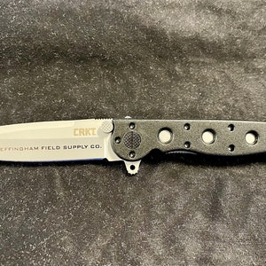 May include: A black folding knife with a silver blade. The blade has the text "CRKT EFFINGHAM FIELD SUPPLY CO." on it.