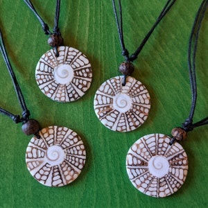 Könnte beinhalten: Vier Halsketten mit braunen Holzperlen und runden weißen und braunen Muschelanhängern. Die Anhänger haben ein Spiralmuster.