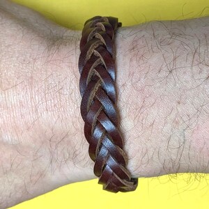 May include: A brown leather braided bracelet. The bracelet is woven with a simple, classic design.