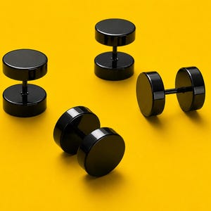 Könnte beinhalten: Mehrere schwarze, hantelförmige Ohrringe auf einem leuchtend gelben Hintergrund. Die Ohrringe haben ein kreisförmiges Design mit einem zentralen Stab. Die Ohrringe sind aus einem glänzenden, reflektierenden Material gefertigt.