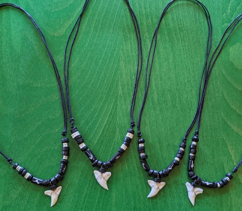 May include: Three black cord necklaces with white and black bead accents and a white shark tooth pendant.