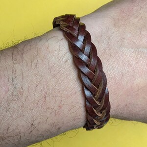 May include: A brown leather braided bracelet. The bracelet is woven with a simple, classic design.