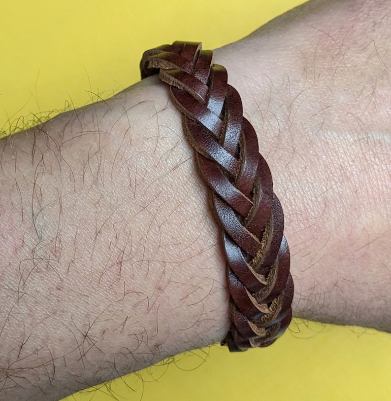May include: A brown leather braided bracelet. The bracelet is woven with a simple, classic design.