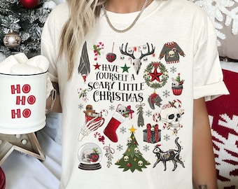May include: White t-shirt with a spooky Christmas design. The design features a skull, a cat, a Christmas tree, and the text "Have yourself a scary little Christmas".
