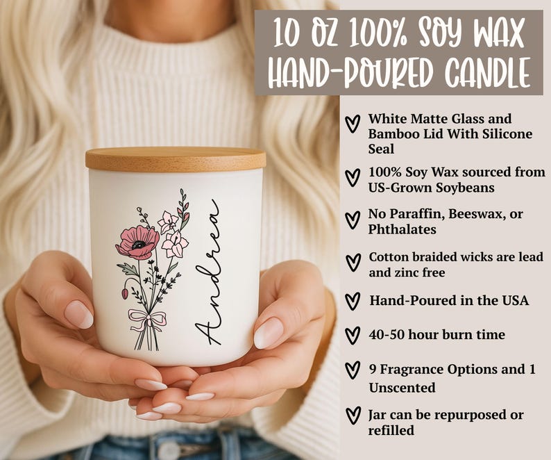 May include: A white matte glass candle with a bamboo lid, featuring a floral design and the name "Andrea." The candle is hand-poured in the USA and made with soy wax. The label reads "10 OZ 100% SOY WAX HAND-POURED CANDLE."