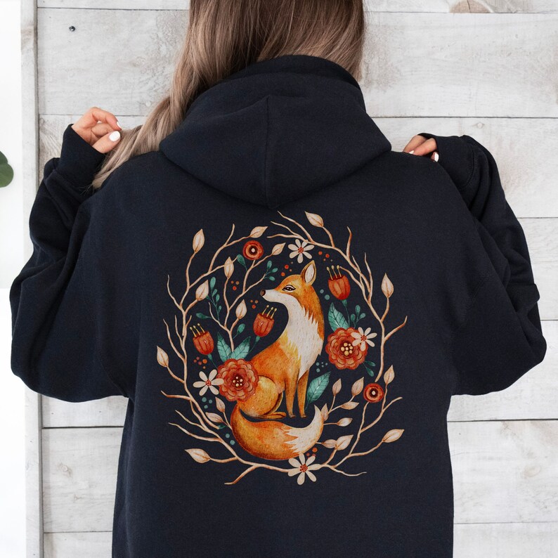 May include: Black hooded sweatshirt with a graphic print of an orange fox sitting in a circle of brown branches and colorful flowers.