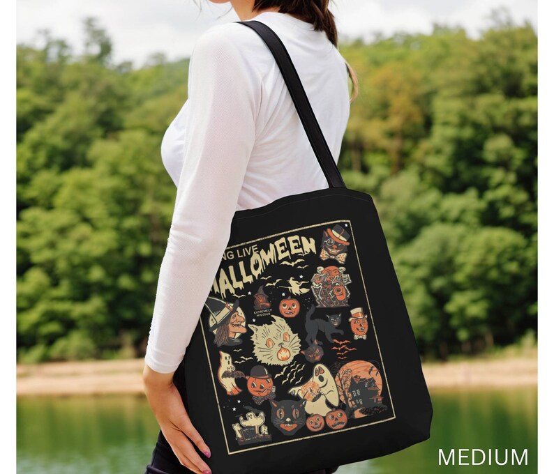 May include: A black tote bag with a vintage-style illustration of Halloween characters. The bag features a black cat, a ghost, a witch, and pumpkins. The text "Going Live Halloween" is printed on the bag.