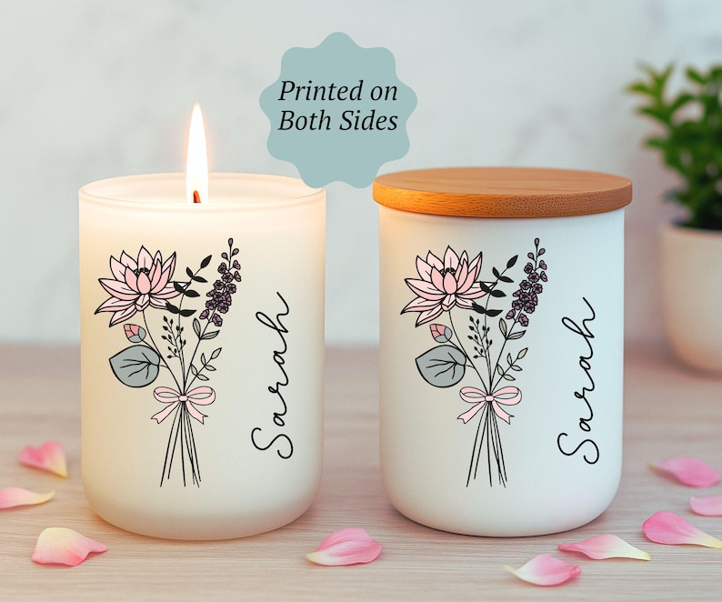 May include: Two white candles with floral designs and the name "Sarah" printed on them. One candle is lit, and the other has a wooden lid. The floral design includes pink lotus flowers, purple sprigs, and green leaves. The text "Printed on Both Sides" is also visible.