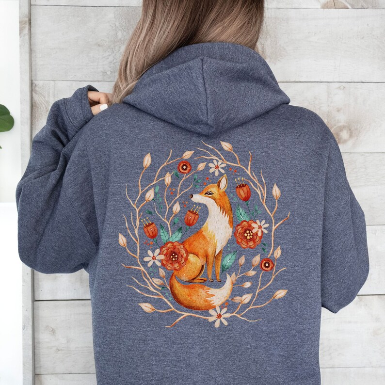 May include: A dark blue hooded sweatshirt with a graphic of a fox in a circle of flowers and branches. The fox is orange and white, and the flowers are orange, white, and green.