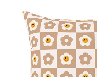 May include: A brown and white checkered throw pillow with a pattern of yellow smiley faces inside white flowers.