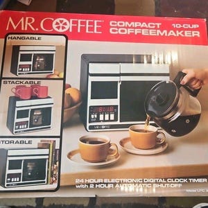 May include: A Mr. Coffee compact 10-cup coffeemaker in its original box. The box features images of the coffee machine, coffee cups, and a digital clock display. The box also shows the coffeemaker pouring coffee into a cup.