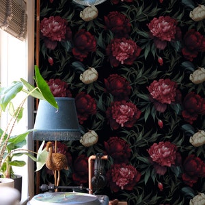 May include: A black and green floral wallpaper with large red and pink peonies. A gold flamingo lamp with a blue lampshade sits on a wooden table with a record player.