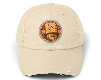 Könnte beinhalten: Eine beige, abgenutzte Baseballkappe mit einem runden Aufnäher, der eine Retro-Berglandschaft mit einem See, Bäumen und einer Sonne zeigt. Der Aufnäher hat einen blauen, orangen und roten Rand.