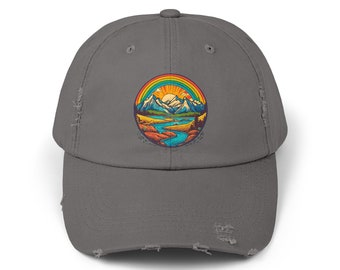 Könnte beinhalten: Eine graue, abgenutzte Baseballkappe mit einem bunten Bergmotiv und einem Regenbogen-Grafik. Die Szene zeigt einen See, Berge und einen Sonnenuntergang.