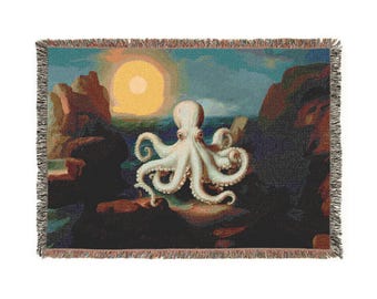 May include: Woven throw blanket with a white octopus design set against a seascape. The artwork shows a large octopus with curled tentacles, set against a sunset with rocky cliffs. The blanket has a fringed edge and a textured appearance.