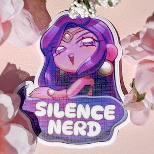 May include: A die-cut sticker featuring a stylised character with long purple hair, a gold forehead gem, and large hoop earrings. The character is positioned above a purple and blue gradient banner with the white text SILENCE NERD.