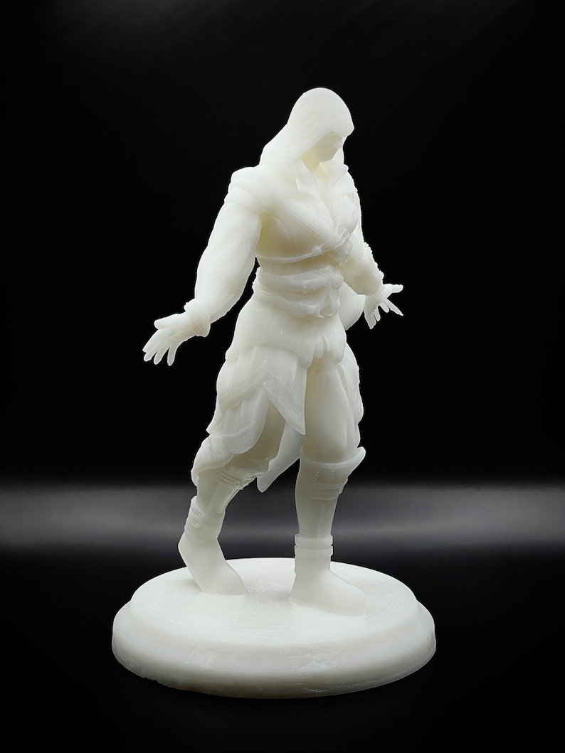 May include: White 3D printed figurine of a person wearing a hooded cloak and holding their hands out. The figurine is standing on a round base.