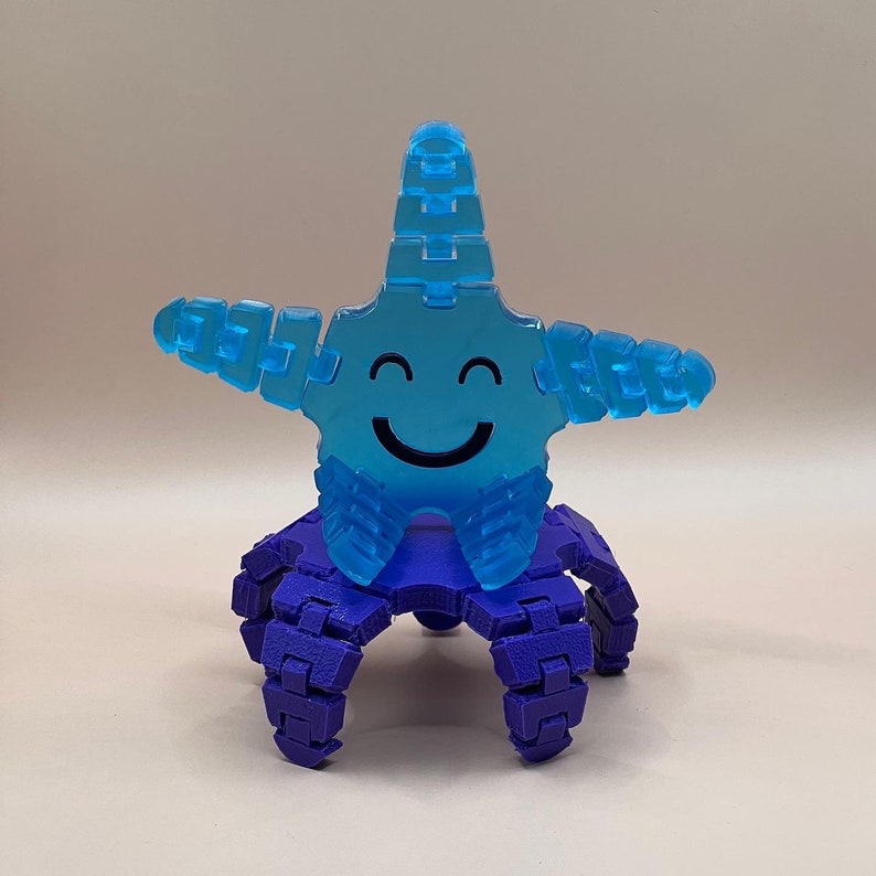 May include: A blue smiling starfish toy with purple legs. The starfish has a happy face and is made of plastic.