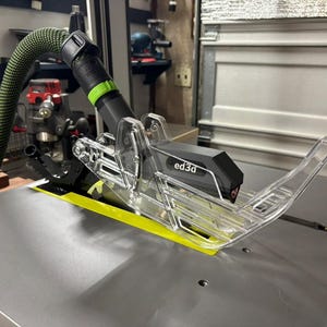 May include: A clear plastic dust collection system for a table saw, with a black hose and a gray ed3d label.