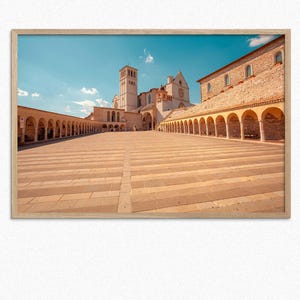 May include: A framed photograph of a large, white stone building with a courtyard in front. The building has a tall tower and many arches. The courtyard is paved with stone and has a striped pattern.