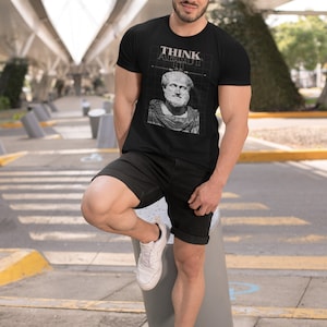 May include: A black t-shirt featuring a white graphic of a man's bust with the text "THINK ABOUT IT" above it.