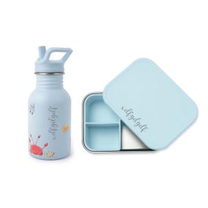 May include: A light blue water bottle and lunchbox set. The water bottle has a flip-top lid and features sea creature illustrations. The lunchbox has a light blue lid and a stainless steel interior with two compartments. The text "xdfgdgdf" is on both items.