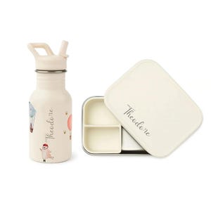 May include: Off-white water bottle with a straw and a matching lunchbox. The bottle features hot air balloon illustrations and the name "Theodore". The lunchbox has a divided interior and the name "Theodore" on the lid.