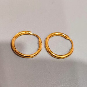 May include: A pair of gold hoop earrings. The earrings are simple and classic, with a smooth finish.