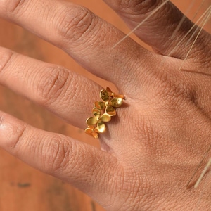 Può includere: Un anello d'oro con un design di più piccole forme di fiori.