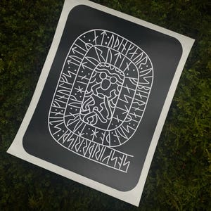 May include: Black and white sticker featuring a white design of a creature with runes surrounding it. The runes are in a circular pattern around the creature. The sticker is on a green mossy surface.