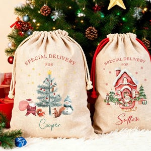 Pode incluir: Dois sacos de presente bege com cordão de tecido tipo estopa. O saco esquerdo apresenta uma árvore de Natal, o Pai Natal, um boneco de neve e o nome Cooper. O saco direito mostra uma casa vermelha, o Pai Natal num trenó e o nome Sutton. Ambos têm o texto Special Delivery For.
