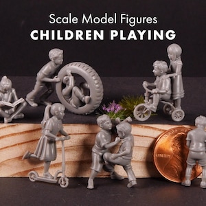 以下が含まれることがあります： Scale Model Figures CHILDREN PLAYINGと書かれた灰色のスケールモデルフィギュアのセット。読書、タイヤ転がし、三輪車、キックスクーター、レスリングをする子供たちの姿が、銅貨の横に配置されています。