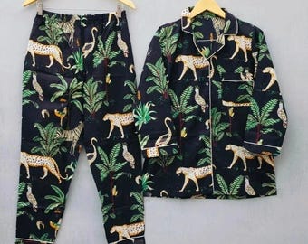Könnte beinhalten: Schwarzes Pyjama-Set mit Dschungel-Print. Das Set beinhaltet ein Hemd mit Knöpfen und eine passende Hose. Der Print zeigt Leoparden, Vögel und Palmen in verschiedenen Farben.