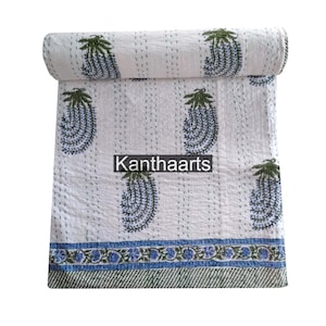 May include: White and blue paisley patterned quilt with green accents. The quilt is rolled up, showcasing the intricate design and stitching. The text "Kanthaarts" is visible on the quilt.