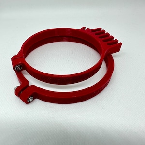 May include: Red plastic embroidery hoop with a textured surface and a locking mechanism. The hoop is designed for use with embroidery floss or yarn.