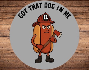 Puede incluir: Ilustración de dibujos animados de un personaje de perrito caliente con un casco de bombero y sosteniendo un hacha. El texto "GOT THAT DOG IN ME" está en un diseño circular alrededor del perrito caliente. El perrito caliente tiene una expresión enojada y usa botas negras.