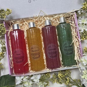 Puede incluir: Un juego de regalo de cuatro botellas transparentes con tapas plateadas, cada una llena de un l&iacute;quido de diferente color: rojo, amarillo, morado y verde. Las botellas est&aacute;n etiquetadas como "Rose", "Vitamin C", "Lavender" y "Aloe Vera".