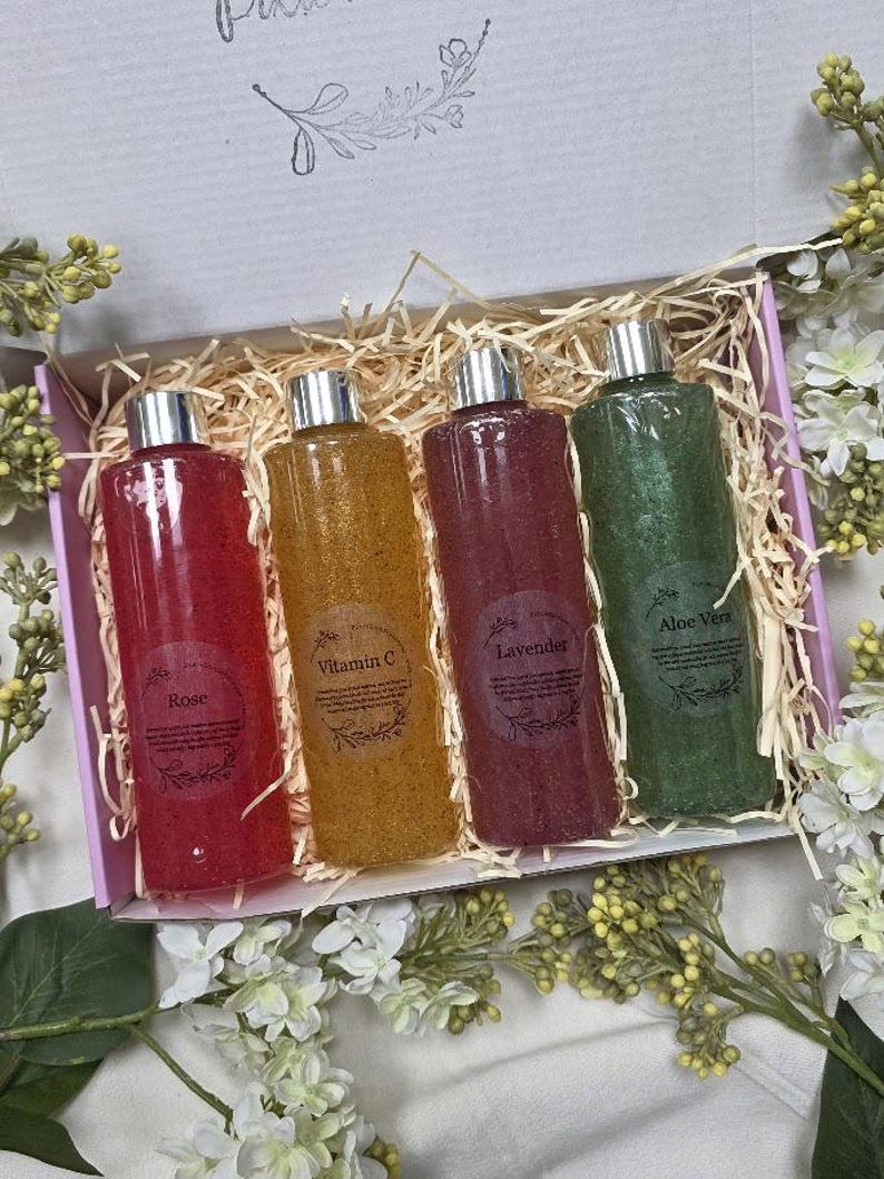 Puede incluir: Un juego de regalo de cuatro botellas transparentes con tapas plateadas, cada una llena de un l&iacute;quido de diferente color: rojo, amarillo, morado y verde. Las botellas est&aacute;n etiquetadas como "Rose", "Vitamin C", "Lavender" y "Aloe Vera".