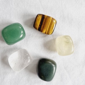 May include: Five tumbled stones in various colors and shapes, including green, clear, yellow, brown, and dark green.