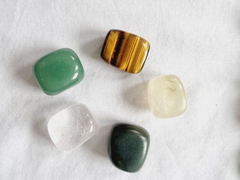 May include: Five tumbled stones in various colors and shapes, including green, clear, yellow, brown, and dark green.