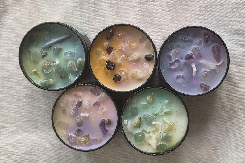 Pu&ograve; includere: Sei piccole candele con cera di diversi colori e cristalli incorporati. Le candele sono in contenitori neri.