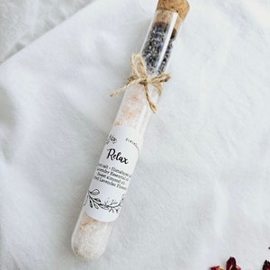 May include: A glass test tube filled with Himalayan salt, lavender essential oil, sweet almond oil, and dried lavender flowers. The label reads "Relax" and lists the ingredients.