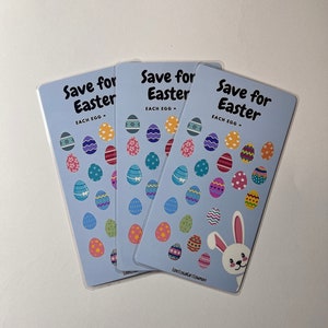 May include: Three blue cards with the text "Save for Easter" and a bunny rabbit illustration. Each card has a grid of 24 colourful Easter egg stickers.