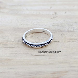 May include: A silver ring with a rope-like design around the band. The ring is marked with the number "925" on the inside.