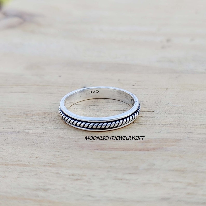 May include: A silver ring with a rope-like design around the band. The ring is marked with the number "925" on the inside.
