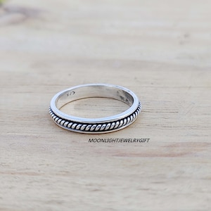 May include: A silver ring with a rope-like design around the band.